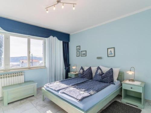 ein blaues Schlafzimmer mit einem Bett und zwei Fenstern in der Unterkunft Apartments Villa Kapelica in Barbat na Rabu