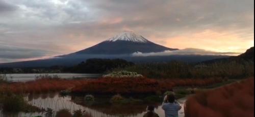 a woman standing in front of a mountain at sunset at Guest house En in Fujiyoshida