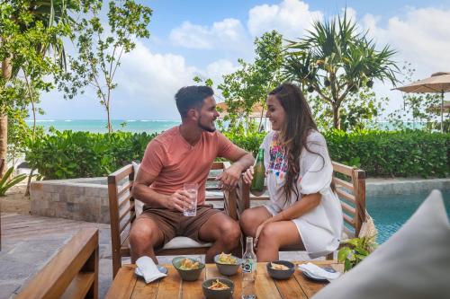 a man and woman sitting on a bench with wine glasses at Alea Tulum in Tulum