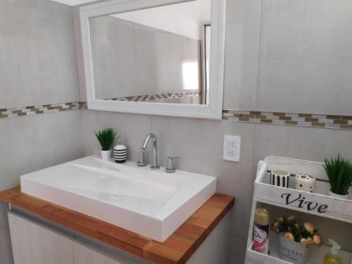 y baño con lavabo blanco y espejo. en Loft las rosas en Villa María