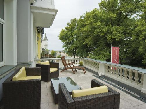 a balcony with chairs and tables on a building at KurparkHotel Warnemünde in Warnemünde