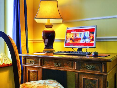 a desk with a computer and a lamp on it at KurparkHotel Warnemünde in Warnemünde