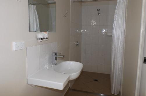 a white bathroom with a sink and a shower at Three Moon Motel in Monto