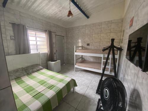 ein Schlafzimmer mit einem Bett mit einer grünen und weißen Decke in der Unterkunft Cantinho MurchioBom in Peruíbe