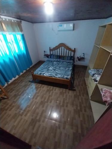 1 dormitorio con 1 cama en una habitación con cortinas azules en Alojamiento UMA en Puerto Iguazú