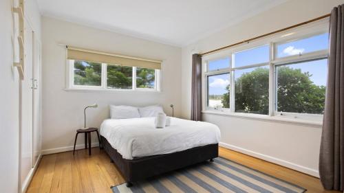 Un dormitorio blanco con una cama y dos ventanas. en Jetty Road on the Beach, en Lakes Entrance