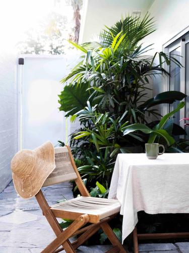 a straw chair sitting next to a table with plants at Tallowwood House Luxury Bed & Breakfast in Port Macquarie