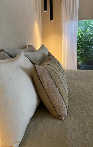 a bed with a pillow on it with a window at Tallowwood House Luxury Bed & Breakfast in Port Macquarie