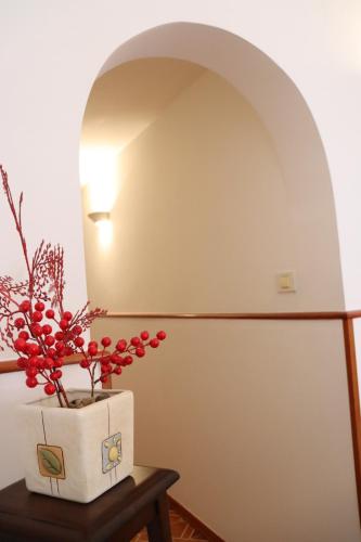 a vase with red flowers on a table with a lamp at Casa Mafalda in Aradeo