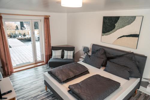 a bedroom with a bed and a chair and a window at Wellnessoase Nordschwarzwald in Neuweiler
