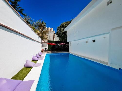 basen z fioletowymi leżakami obok budynku w obiekcie Hostal La Casa de Madera w mieście Mazatlán