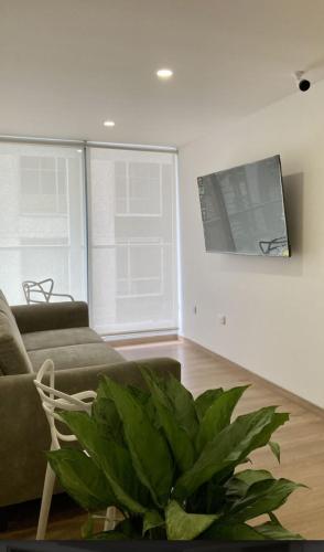 a living room with a couch and a tv on a wall at UhaUs Coliving 302 - Apto 12 habitaciones in Manizales