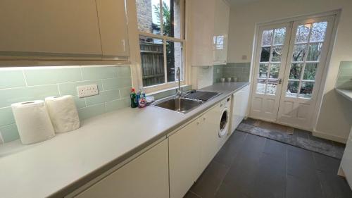 a white kitchen with a sink and a counter at A lovely Three bedroom house in Windsor in Windsor