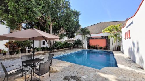 uma piscina com mesa e guarda-sol ao lado de uma casa em HOTEL MARIA ISABEL DE IGUALA em Iguala de la Independencia