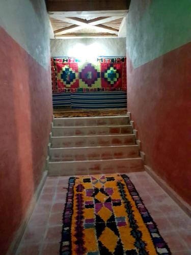 a hallway with stairs with a rug and a mosaic wall at KASBAH Atlas-Aberdouz in Aït Hattab