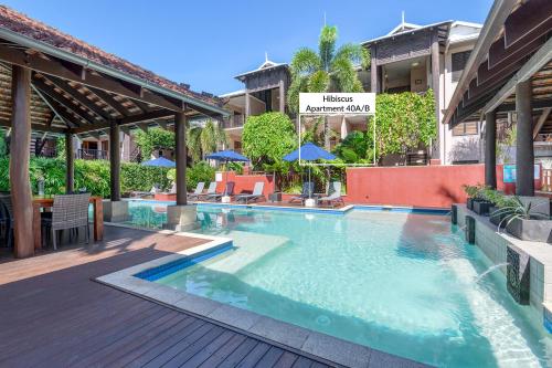 a swimming pool at a hotel with tables and umbrellas at Poolside Villa - Hibiscus 40b in Port Douglas