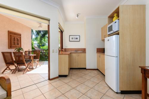 a kitchen with a refrigerator and a table with chairs at Poolside Villa - Hibiscus 40b in Port Douglas