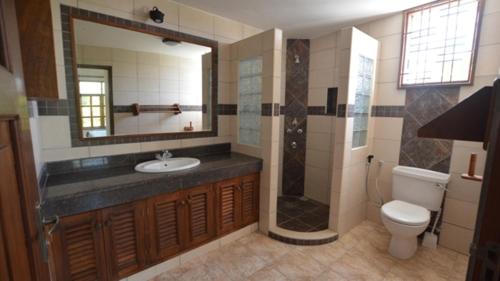 a bathroom with a sink and a shower and a toilet at Diani Pearl in Diani Beach