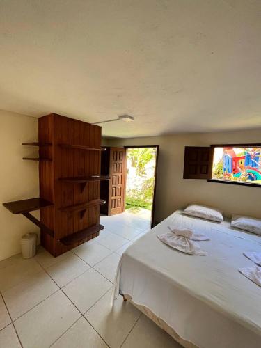 a bedroom with a large white bed and a window at Bem Me Quer Casas in Morro de São Paulo