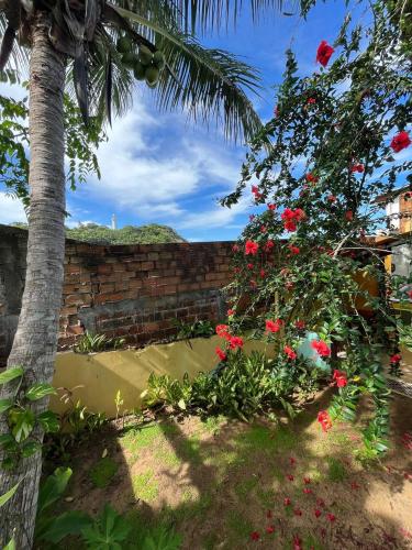 a garden with red flowers and a brick wall at Bem Me Quer Casas in Morro de São Paulo