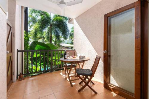a balcony with a table and chairs and a window at Poolside Villa - Hibiscus 40a in Port Douglas