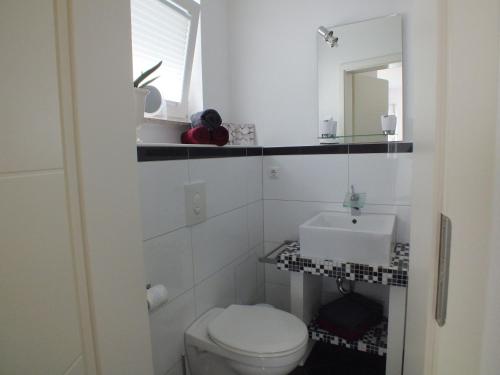 Łazienka z białą toaletą i umywalką w obiekcie Pension Apartment Burscheid w mieście Burscheid