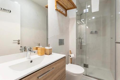 ein Badezimmer mit einem weißen Waschbecken und einer Dusche in der Unterkunft Neptuno Boutique Apartment - No coração do centro de Aveiro in Aveiro
