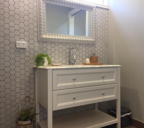 een badkamer met een witte wastafel en een spiegel bij Hamptons In Rye Studio - 3 Mins from Famous Hot Springs! in Rye