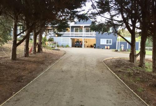 a driveway leading to a blue house with trees at Hamptons In Rye Studio - 3 Mins from Famous Hot Springs! in Rye