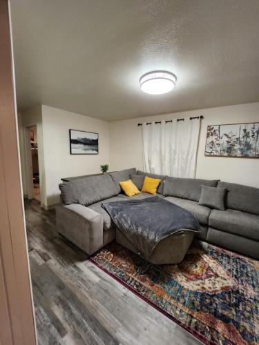a living room with a gray couch and yellow pillows at Luxury Bunkhouse Near Downtown in Fairbanks