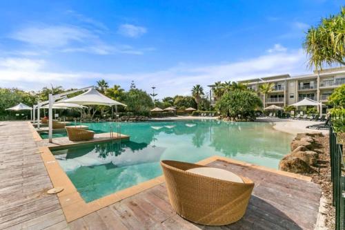 una piscina en un complejo con sillas y sombrillas en Deluxe Dual-Key Apartment in Peppers @ Salt Resort by uHoliday (3BR, 2BR and Hotel Room Options Available) en Kingscliff