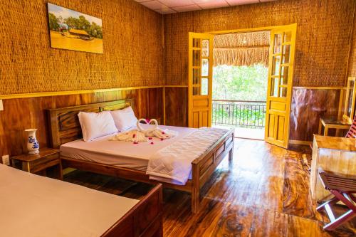 1 dormitorio con 1 cama y puerta a un balcón en MEKONG NATURE LODGE, en Vĩnh Long