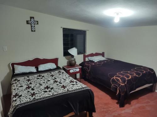 a bedroom with two beds and a cross on the wall at Finca la mora in Morelia