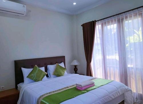 a bedroom with a large bed with a window at Green Palace Homestay in Nusa Penida