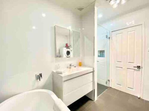 a white bathroom with a sink and a shower at Nelson Bay home on the beach!! in Nelson Bay