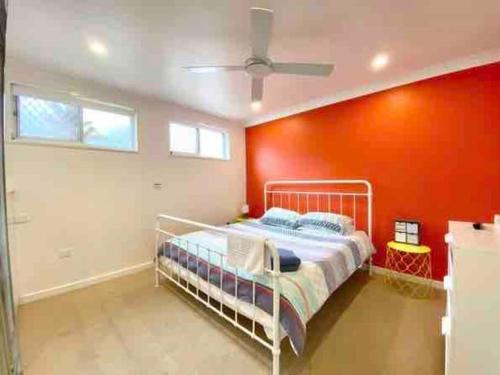 a bedroom with a white bed and a red wall at Nelson Bay home on the beach!! in Nelson Bay