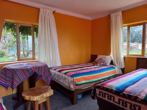 a bedroom with two beds and a table and windows at Musiña Lodge in Amantani