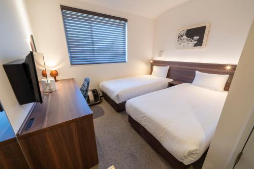 京都的住宿－RESI STAY Jisco Hotel Kyoto Goshonishi，酒店客房设有两张床和电视。