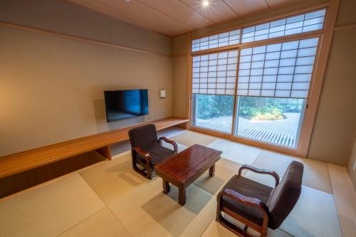 京都的住宿－RESI STAY Jisco Hotel Kyoto Goshonishi，一间设有桌椅和电视的等候室