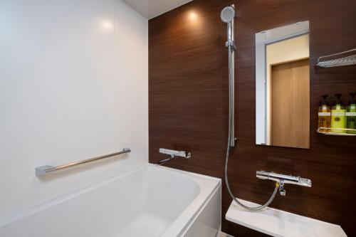 HOTEL MYSTAYS Nishi Shinjuku في طوكيو: حمام مع حوض ومغسلة ومرآة