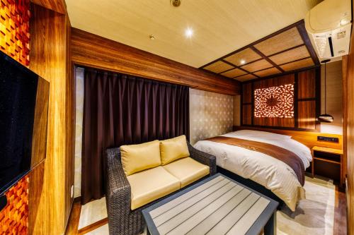 een slaapkamer met een bed, een bank en een tv bij Hotel Lotus Okayama Adult Only -Adult Only in Okayama