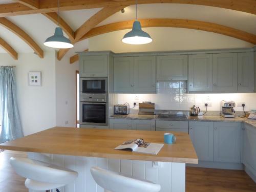 a kitchen with white cabinets and a wooden counter top at High Trodigal in Machrihanish