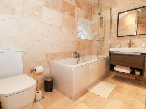 a bathroom with a tub and a toilet and a sink at Springwood Cottage in Holmfirth
