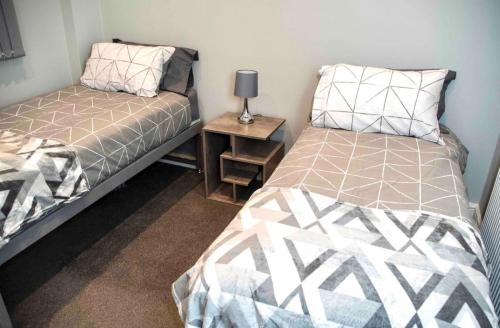 a bedroom with two beds and a table with a lamp at Cosy Convenient 1 BR Flat at Central Stoke Near Hospitals and Univesities in Stoke on Trent