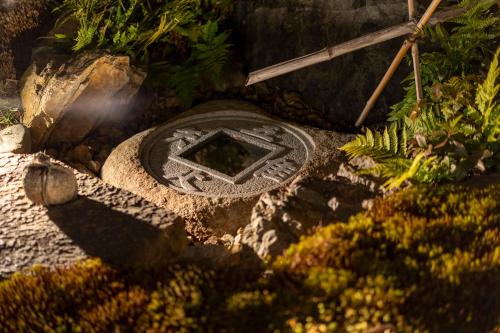 a manhole cover in a garden with plants at RESI STAY Jisco Hotel Kyoto Goshonishi in Kyoto