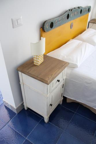 a bed with a white nightstand with a lamp on it at Avocado B&B Beyond in Giardini Naxos