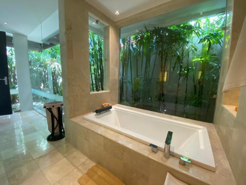 Lotus Luxury Villa Seminyak في سمينياك: حوض استحمام في حمام مع نافذة كبيرة