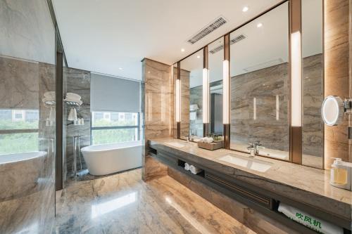 a bathroom with a tub and a sink and mirror at Holiday Inn Zhengzhou Zhongzhou by IHG in Zhengzhou