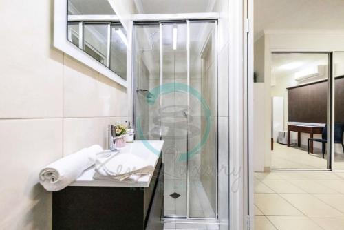 uma casa de banho com um lavatório e uma cabina de duche em vidro. em ZEN FORESHORE Cozy 2-BR, 2-BA Holiday Home + Pool em Nightcliff