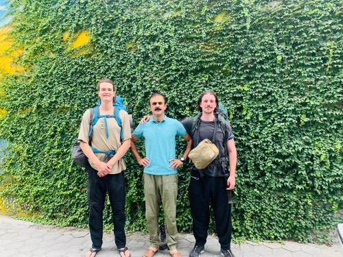 ギルギットにあるNaveed Tourist Innの三人の緑の垣根の前に立つ